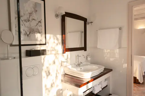 Private bedroom suite with white linens and restored architectural details.