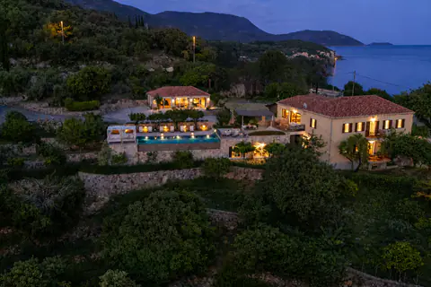 Twilight drone view of the estate, pool, terraced gardens, and bay.
