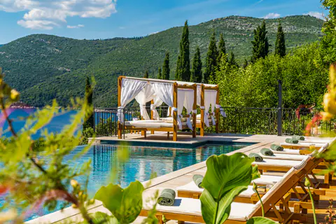 Infinity pool terrace framed by cypress trees and the Konavle hills.