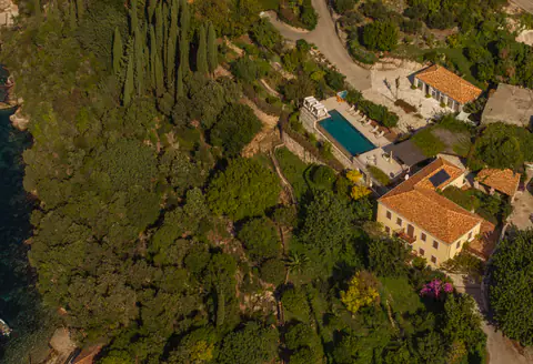 Aerial view of the estate descending through woodland toward the sea.