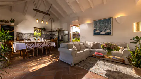 Open-plan living and dining room with terracotta floors and timber beams.