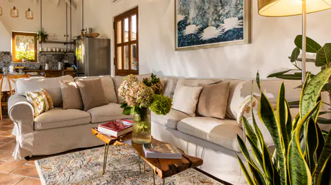 Restored stone living room with white seating and timber ceiling beams.