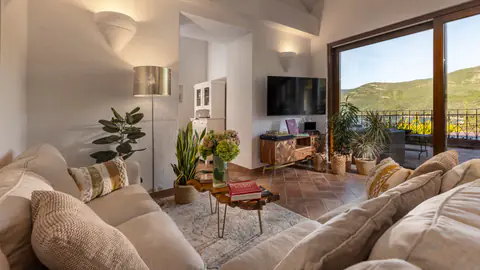 Comfortable living room framed by plants and warm natural light.