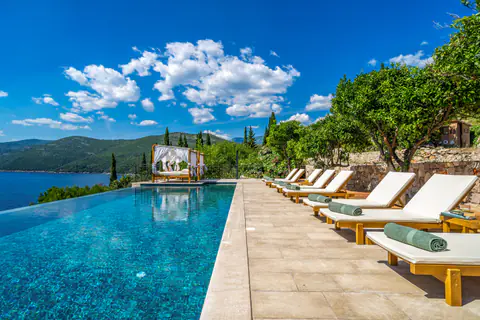 Infinity pool and cabana at sunset above Molunat Bay.