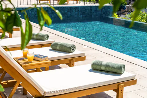 Poolside loungers with towels beside the turquoise water.