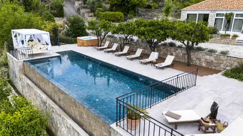 Long infinity-pool view framed by loungers and Mediterranean planting.