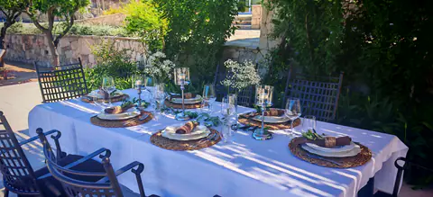 Outdoor dining table prepared beneath a shaded estate terrace.