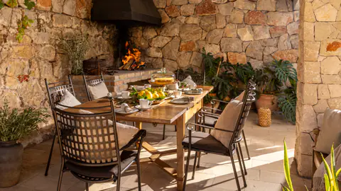 Outdoor dining terrace surrounded by stone walls and greenery.