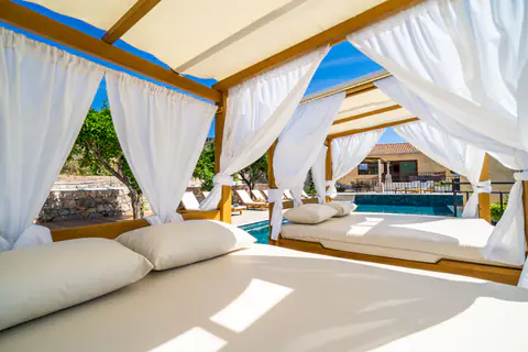 Infinity pool and surrounding sun deck under a clear Mediterranean sky.