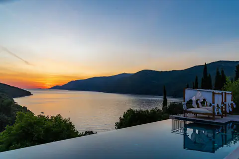 Sunset reflected across the infinity pool and sheltered Adriatic bay.