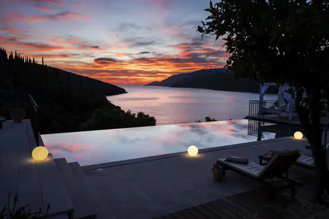 Infinity pool framed by white curtains and the Adriatic beyond.