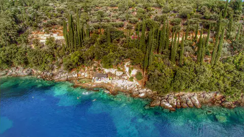 Secluded shoreline terrace beside the clear water of Molunat Bay.