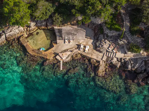 Aerial view of the rocky shoreline and turquoise Adriatic water.