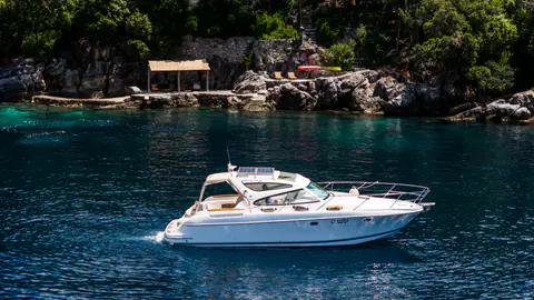Motor yacht passing the estate's rocky sea-access terrace.