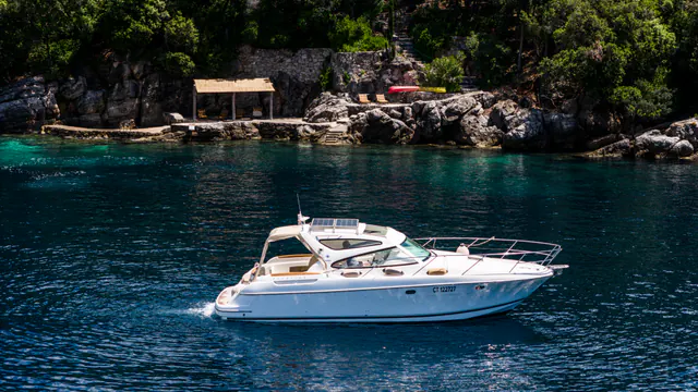 Motor yacht passing the estate's rocky sea-access terrace.